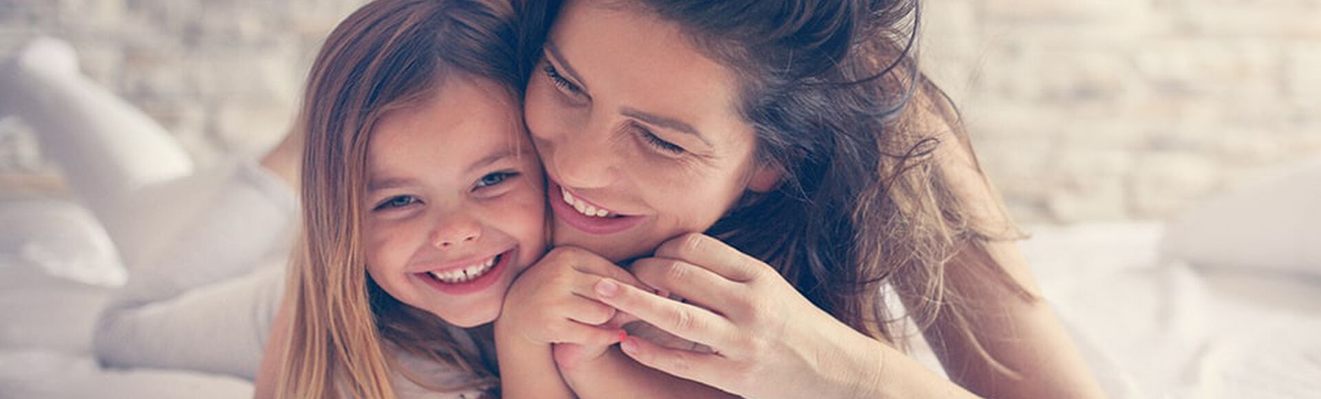 Madre e hija abrazadas en la cama