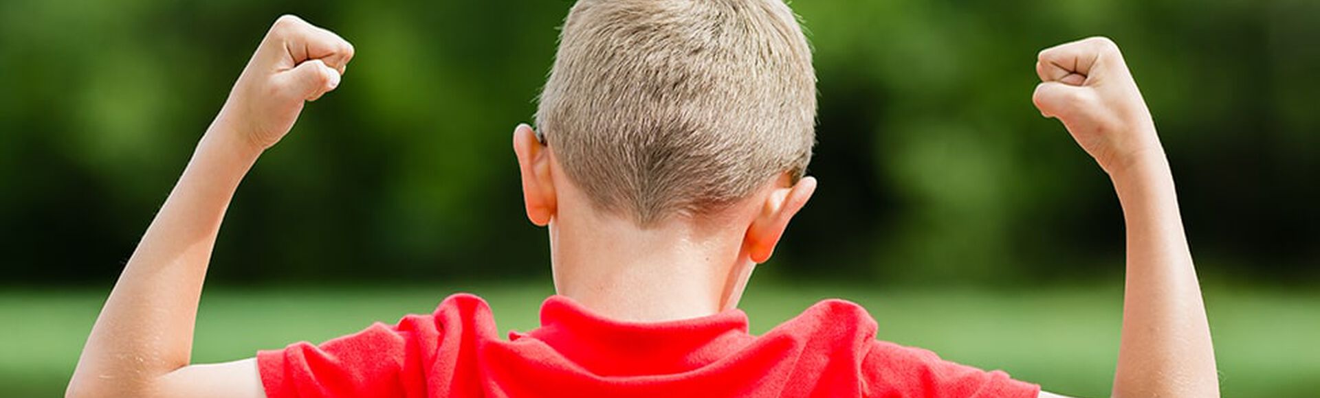 Niño con camisa roja celebra con los brazos