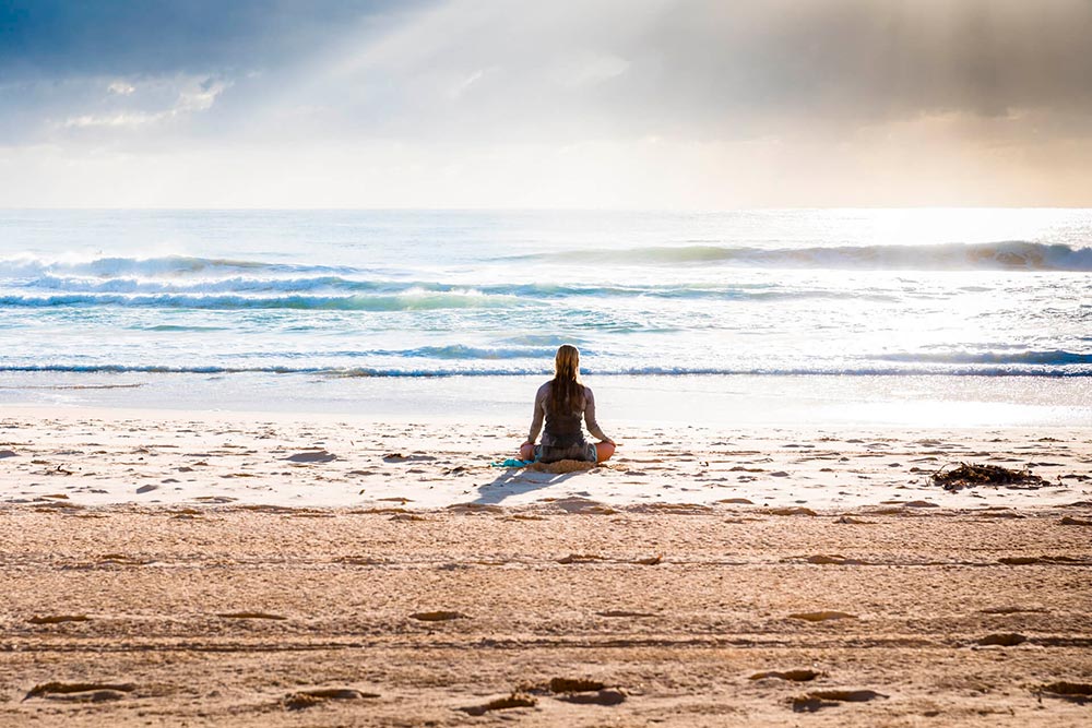 A person standing on top of a sandy beach next to the ocean

Description automatically generated